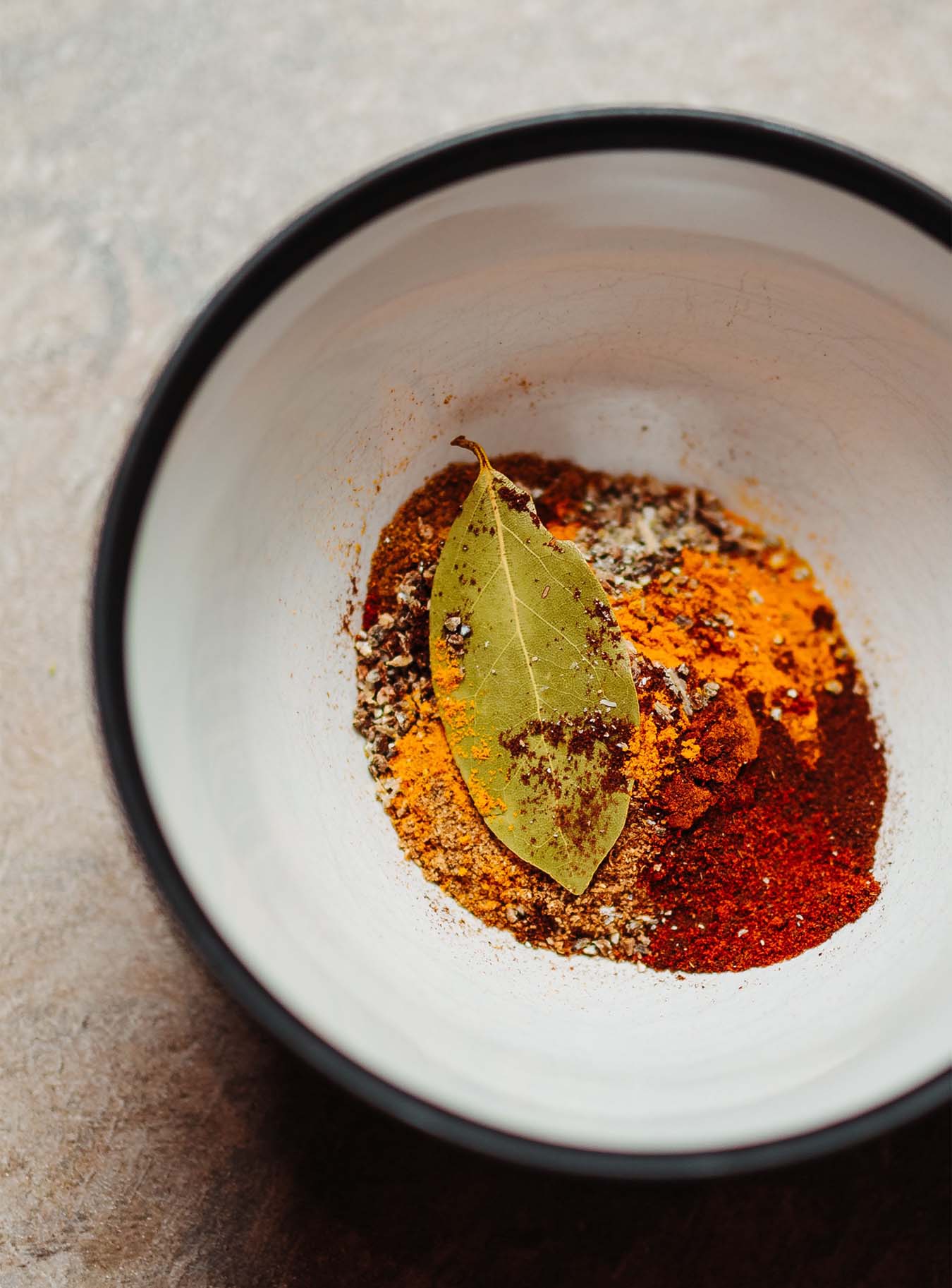 red and orange spices and a bayleaf in a bowl