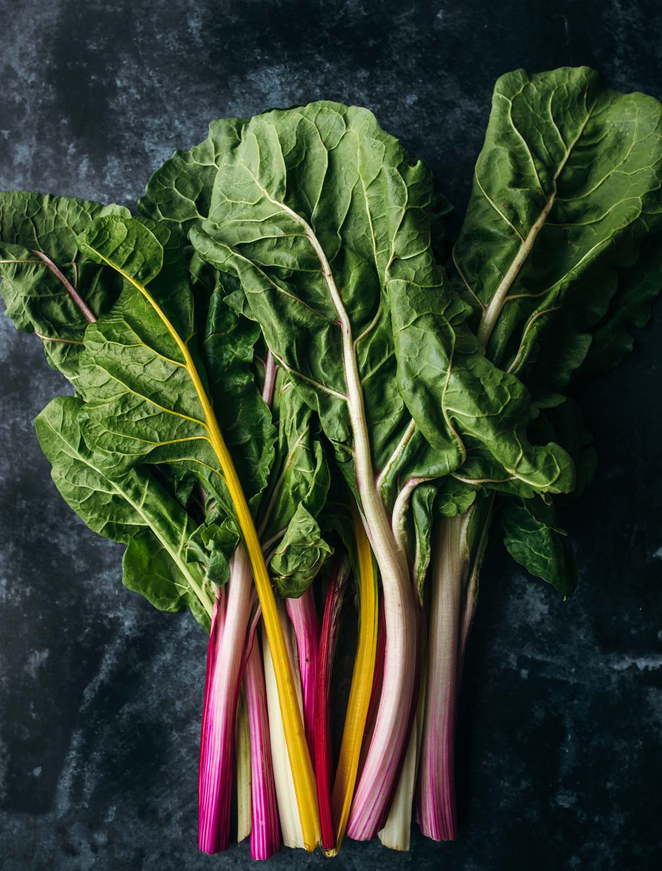 pink, white and yellow rainbow chard on a dark plate