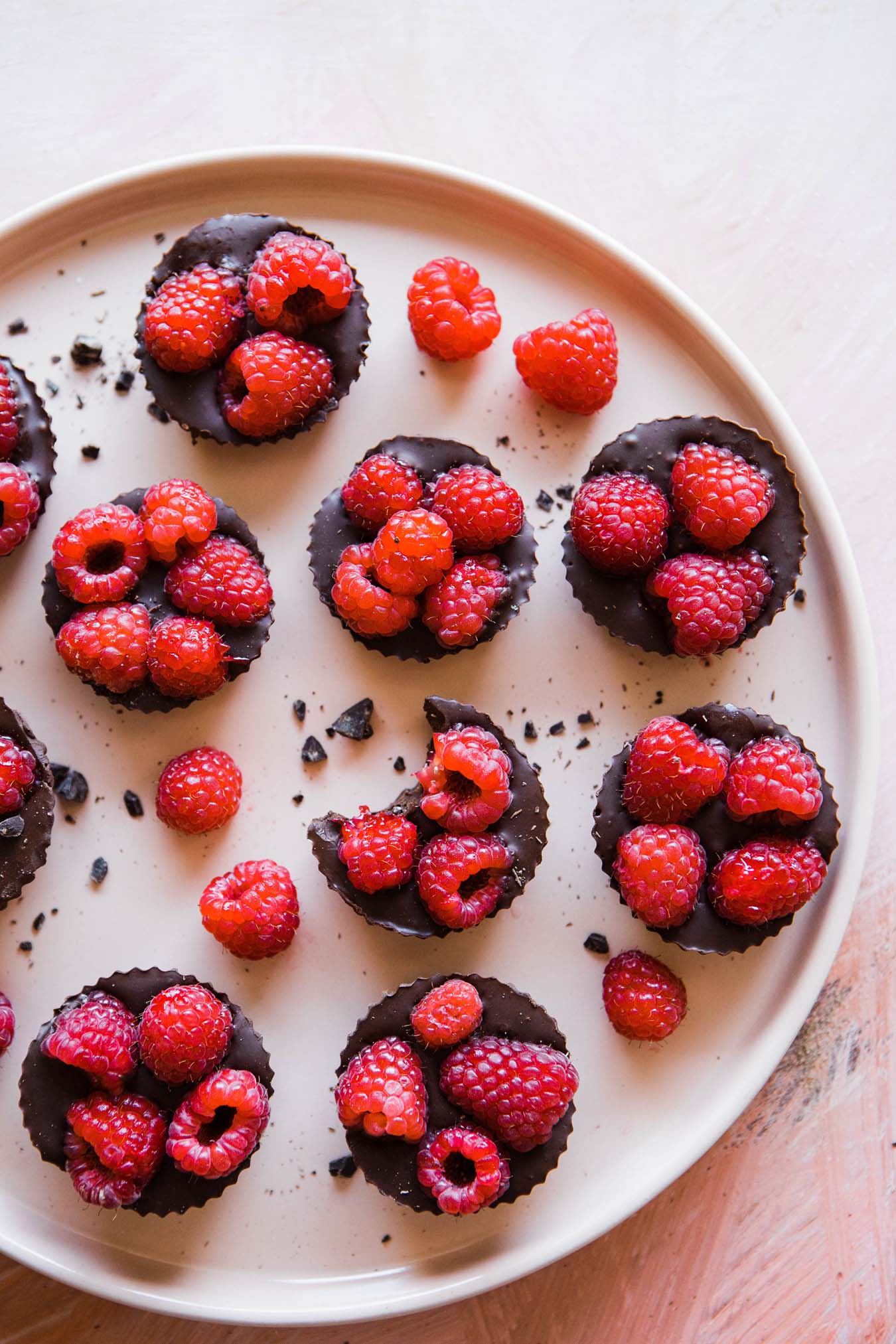 chocolate cakes with raspberries lying on a white plate - one cake is bitten into and some raspberries are lying next to it