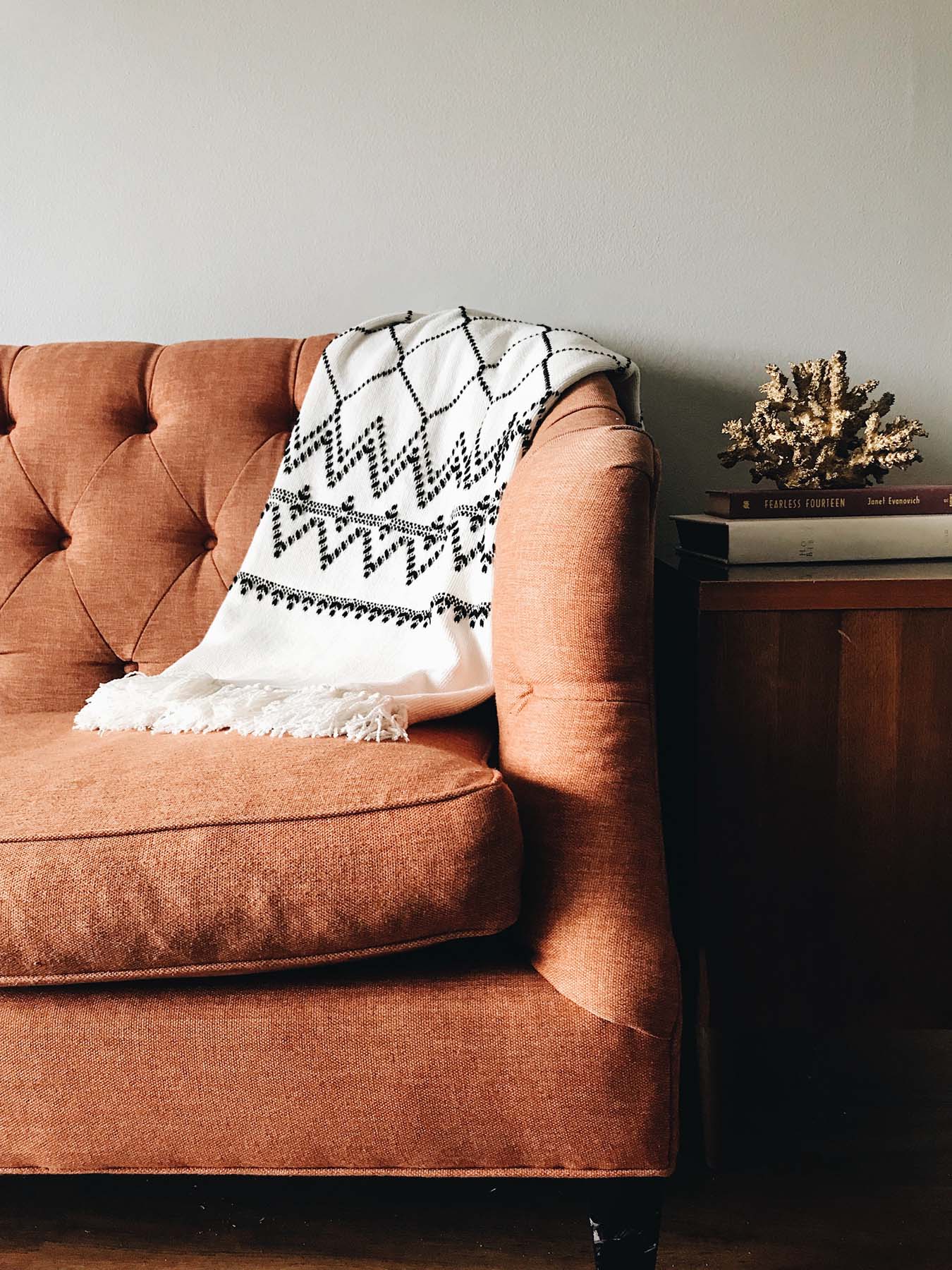 A brown sofa bed with a white and black blanket lying on it.