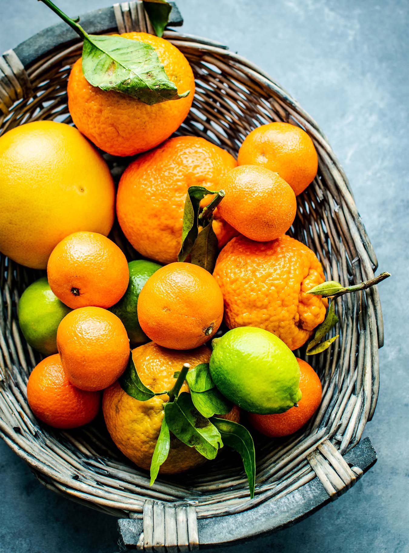 Orangen- und Zitronenfrüchte in grauem Weidenkorb