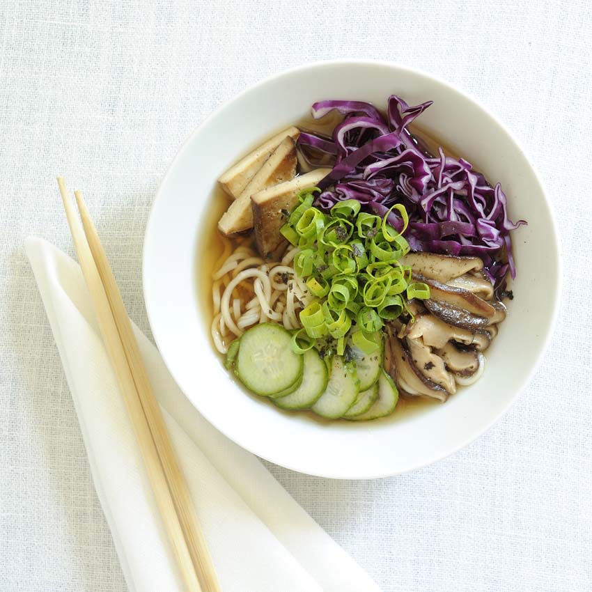 Ramenbowl mit Nudeln, Rotkraut, Pilzen und Tofu - daneben hölzerne Essstäbchen